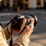 Un photographe tenant un appareil photo professionnel dans une rue urbaine à la lumière du soir