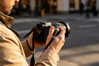 Un photographe tenant un appareil photo professionnel dans une rue urbaine à la lumière du soir